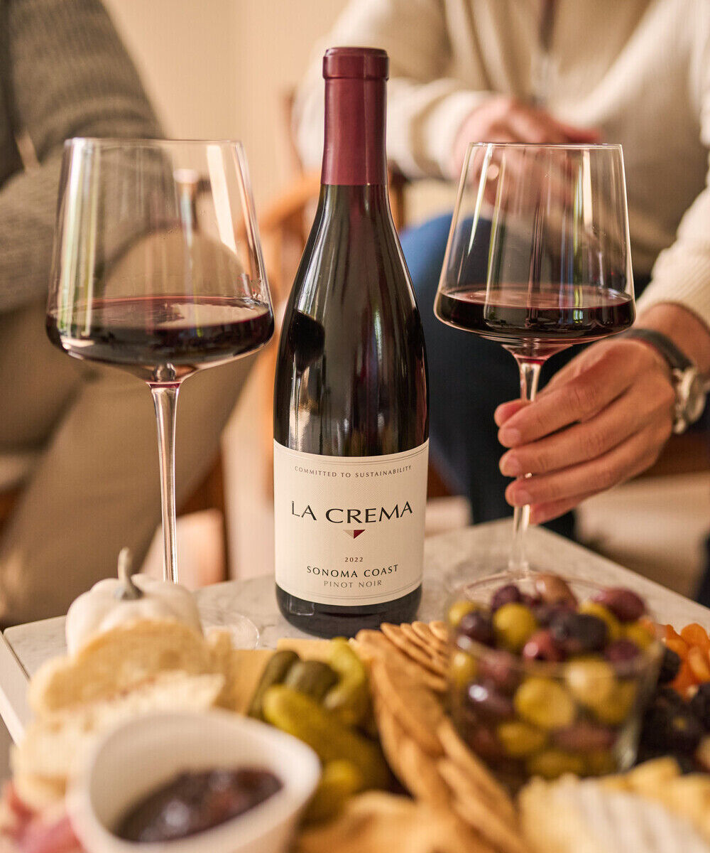 Two people drinking La Crema Pinot Noir with a charcuterie board